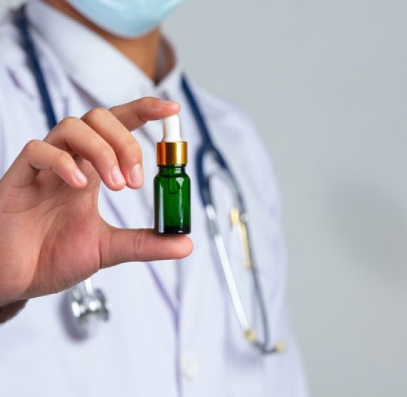 close-up-picture-medical-doctor-holding-bottle-cannabis-oil-white-wall_1150-26702